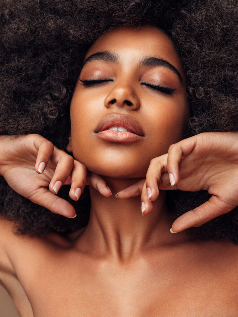 Woman with curly hair and glowing skin for Sculptra treatment content