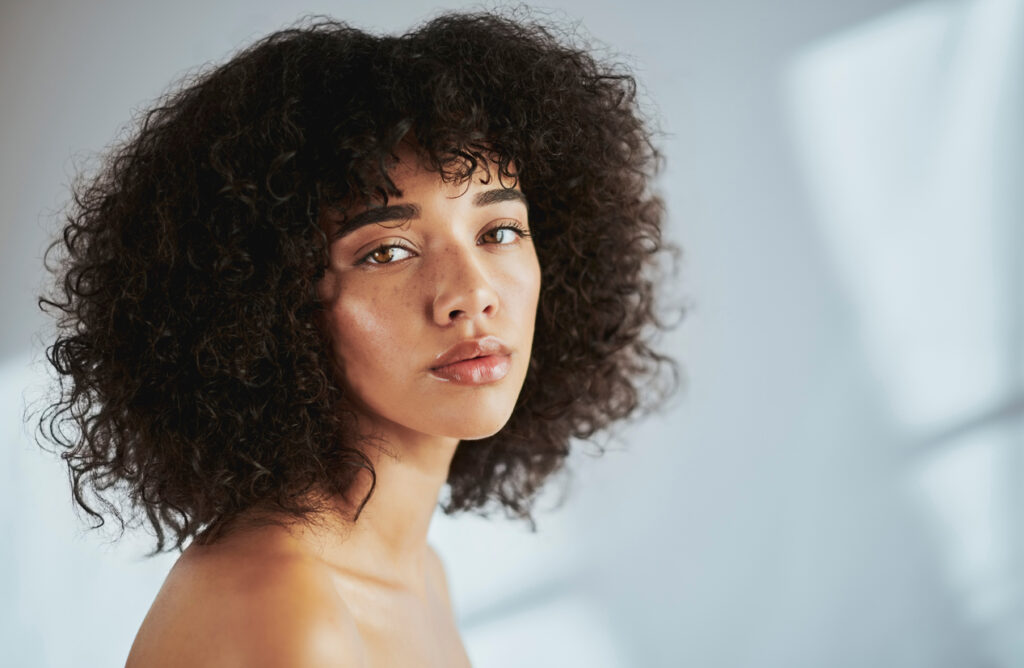 Woman with natural skin and curly hair for Sculptra treatment content