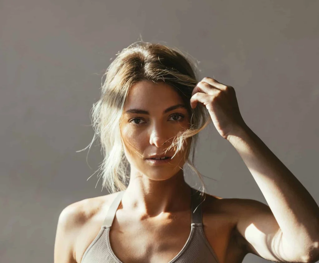 Woman touching her hair and face for beauty and wellness content